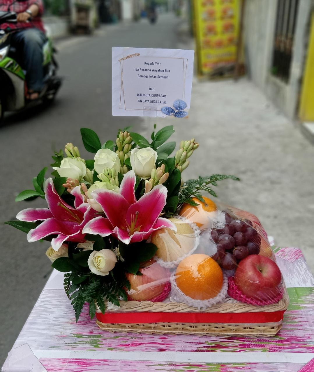 Parcel bunga lily merah pink dan buah segar ucapan semoga lekas sembuh untuk Ida Peranda Wayahan Bun dari Walikota Denpasar IGN Jaya Negara SE