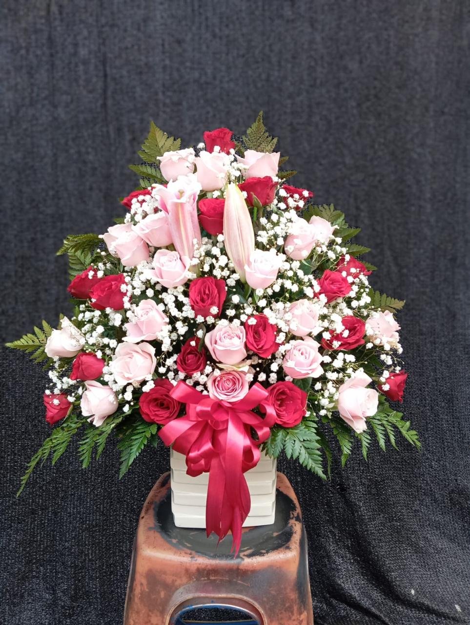 Rangkaian bunga vas mawar merah pink lily dan baby breath dengan pita maroon untuk hadiah